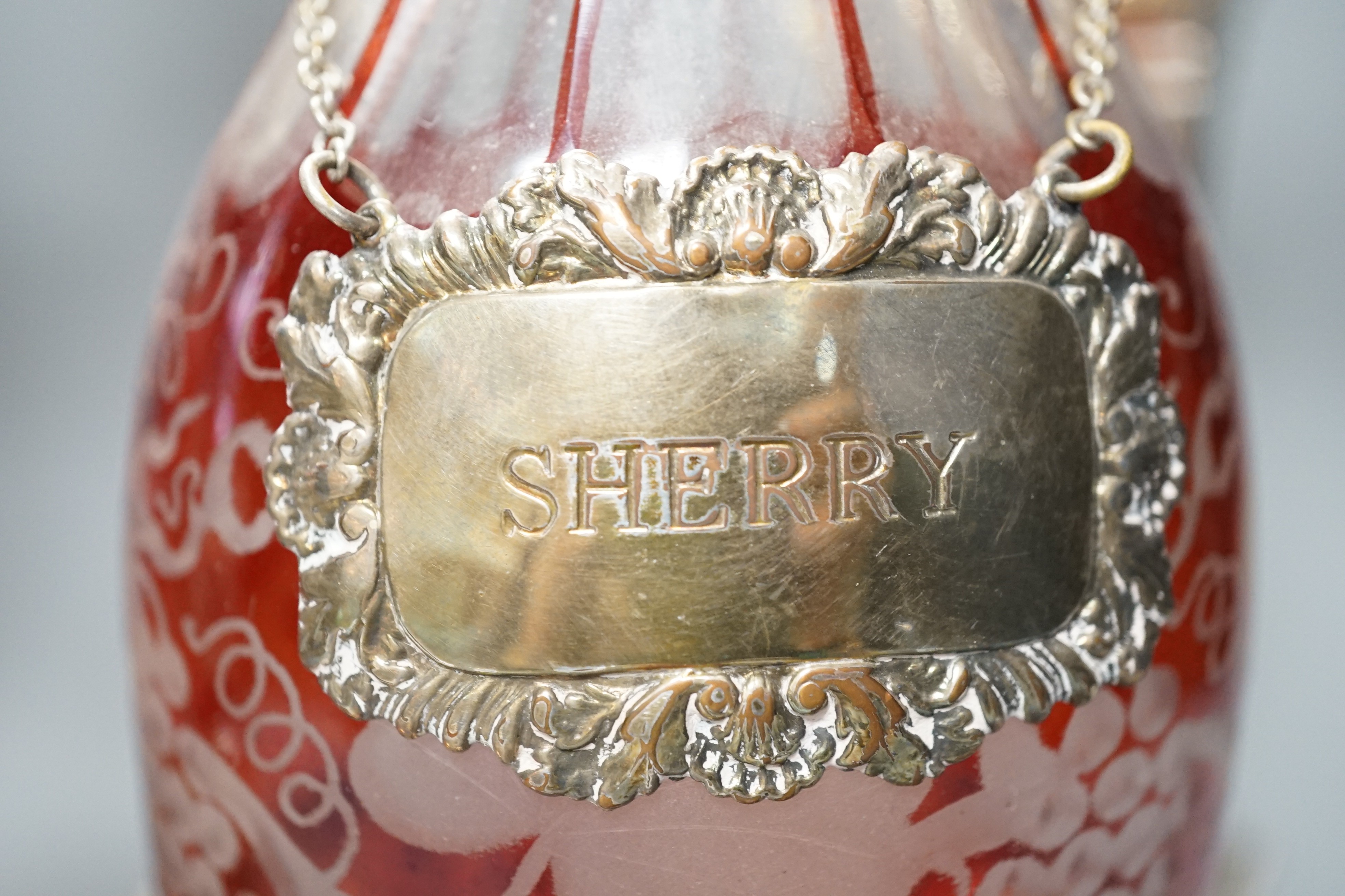 A pair of silver plated two branch, two light candelabra and a pair of silver plated decanter coasters with two ruby flash glass decanters with plated wine labels.